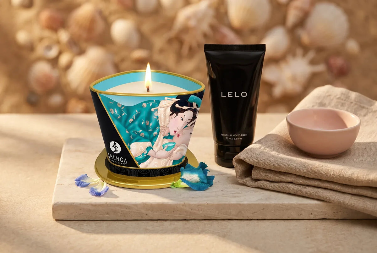 Bougie de massage allumée et flacon de gel sur pierre claire.
