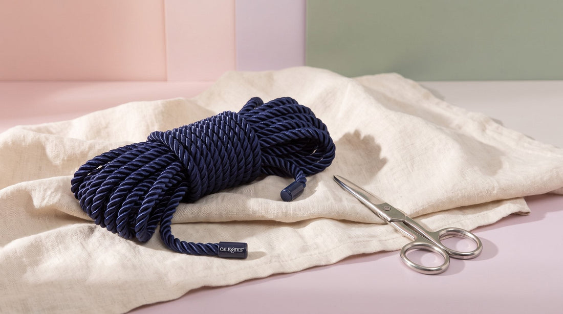 Corde de bondage CalExotics Admiral en nylon bleu lovée sur un lin écru, à côté d’une paire de ciseaux à bout rond