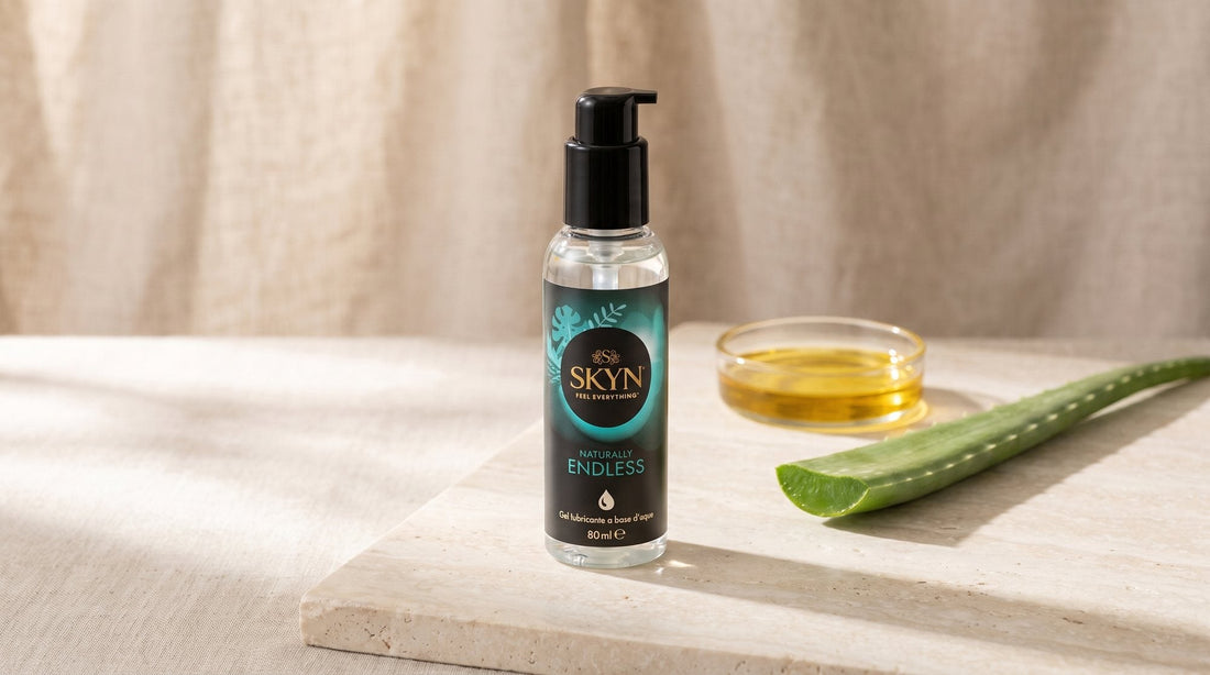 Flacon SKYN Naturally Endless posé sur une pierre claire, près d’une tige d’aloe vera et d’une coupelle d’huile dorée, sur fond de lin