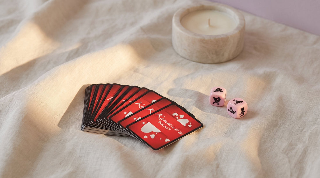 Cartas Kamasutra de Secret Play boca abajo en abanico junto a dos dados eróticos sobre una sábana de lino crudo, con luz cálida