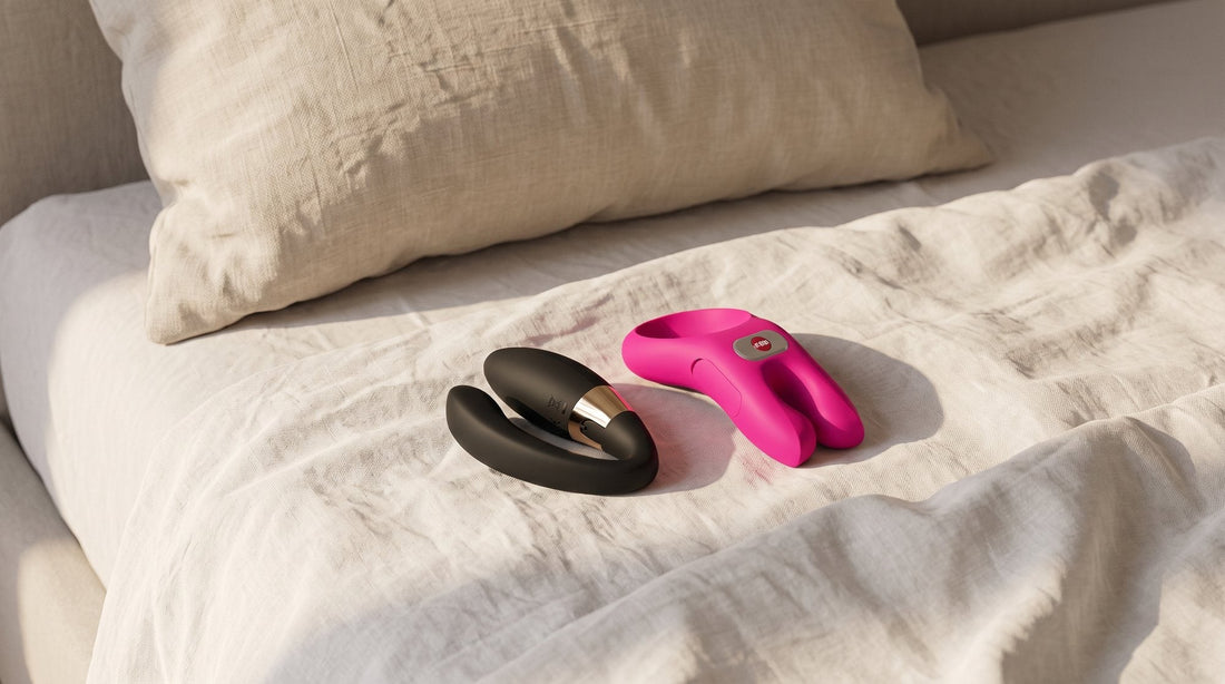 LELO Tiani Duo y anillo FUN FACTORY NŌS Classic sobre una sábana de lino blanco roto, con un cojín beige al fondo y luz suave de tarde