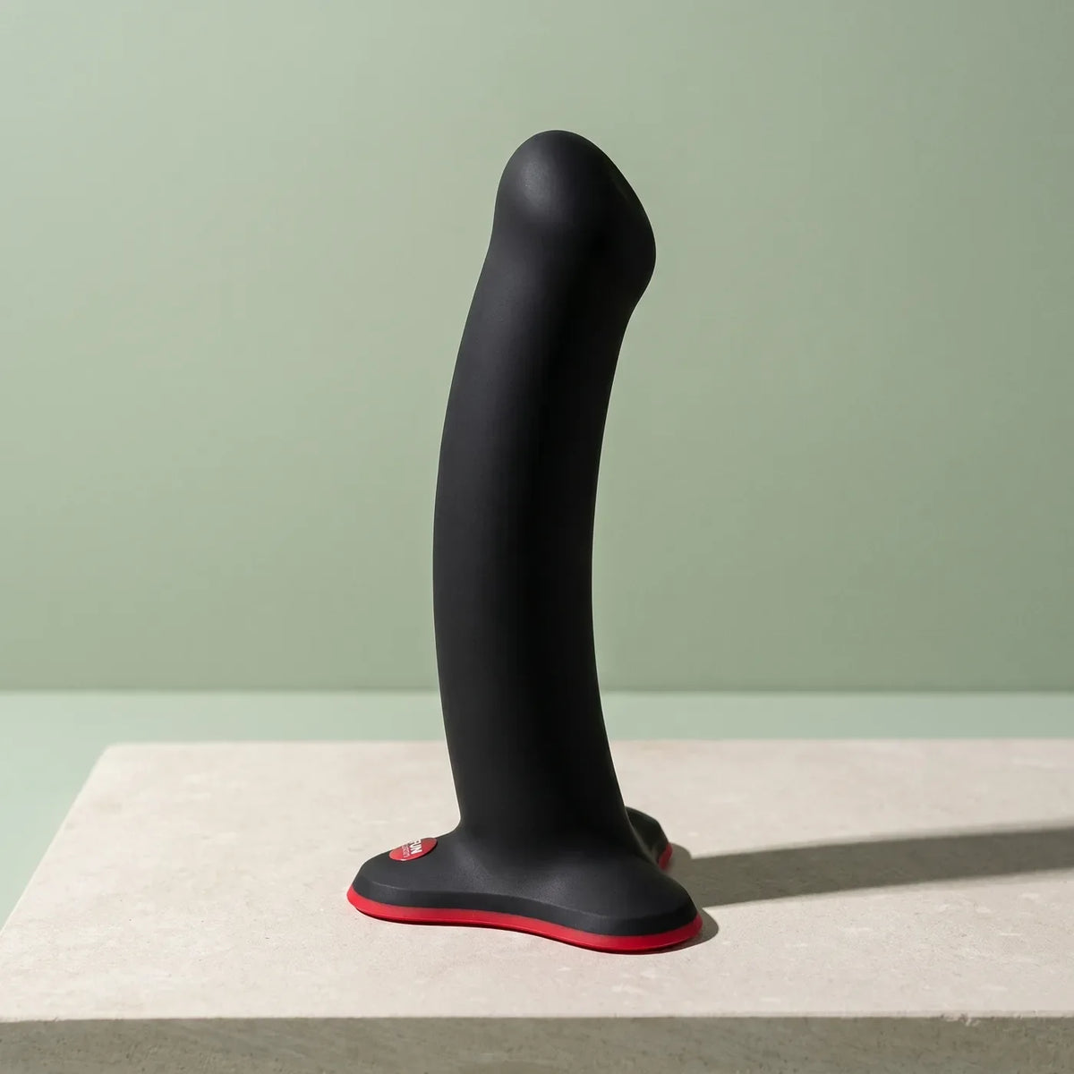 Deux objets de design en silicone coloré posés sur une tablette de pierre claire.