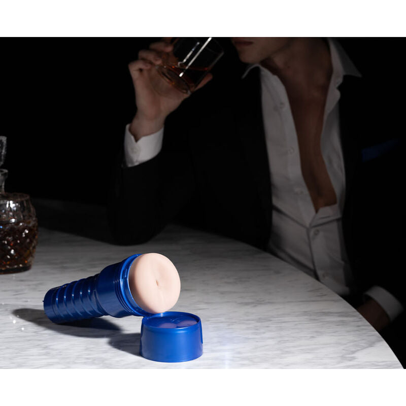 Fleshlight Boost Blast auf einem Marmortisch, im Hintergrund ein Mann im weißen Hemd