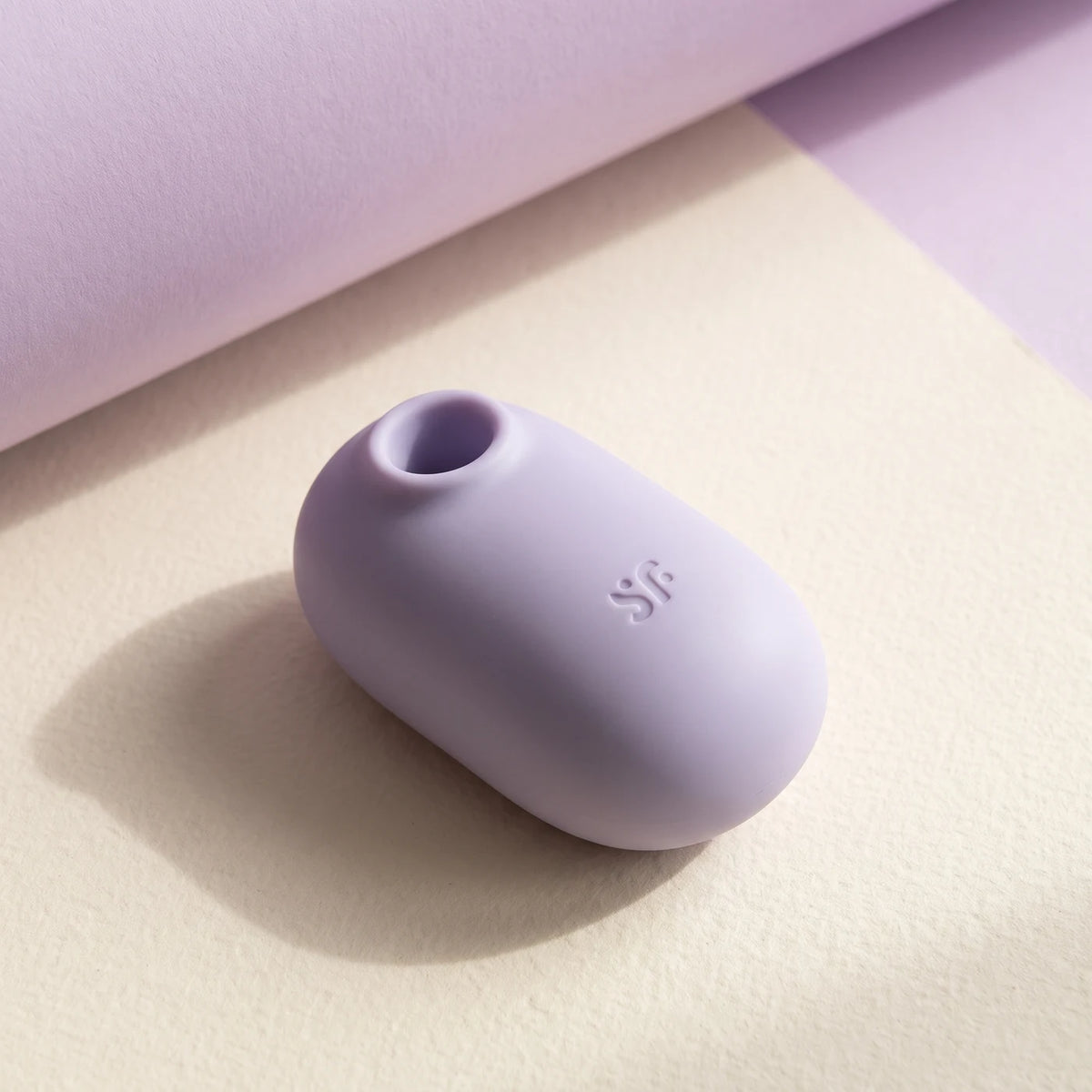 Satisfyer Pro To Go 2 lila sobre papel crema.
