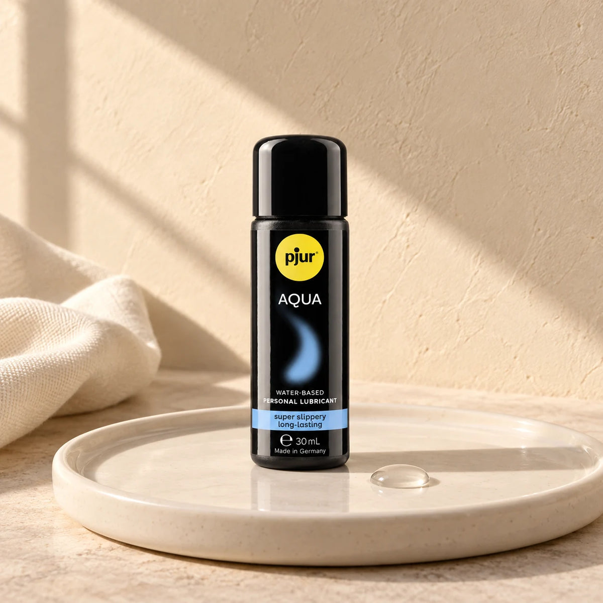 Flacon pjur AQUA 30 ml sur un plateau en céramique claire.