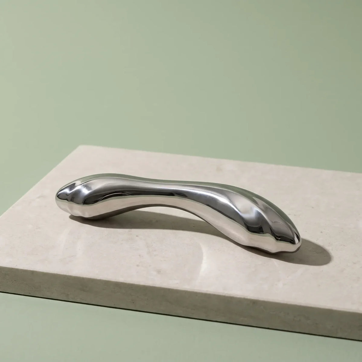 Sculpture en acier inoxydable poli sur pierre claire.