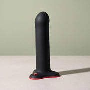 FUN FACTORY Magnum in silicone nero e rosso, in piedi su pietra chiara