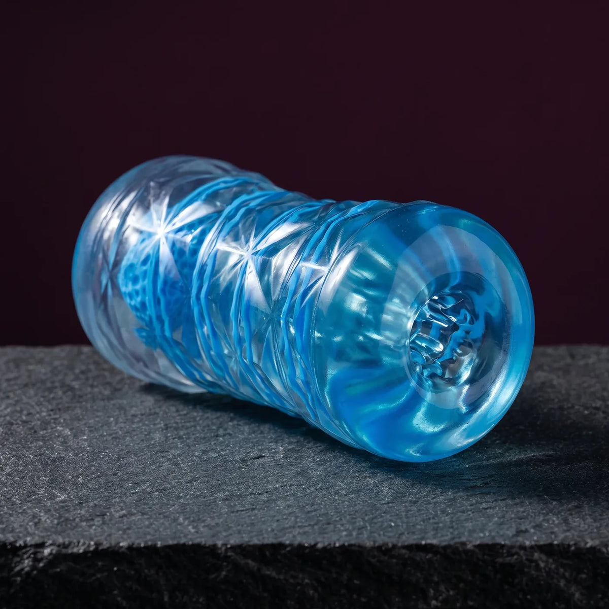 Masturbateur Pretty Love bleu translucide posé sur une pierre graphite.